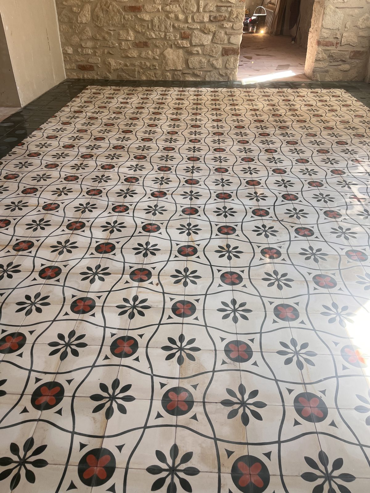 Carreaux de ciment à motif fleuri posés sous un porche en pierre à Castres par TNR Carrelage